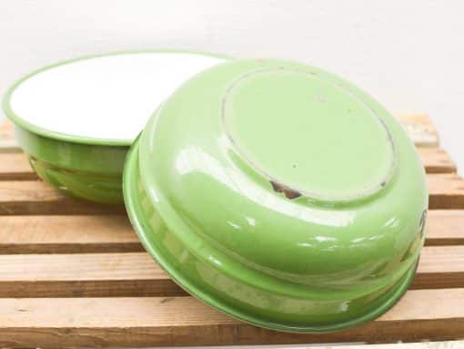 Vibrant green vintage enamel bowls with white interiors, adding charm to any kitchen setting.