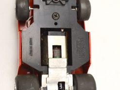 Detailed underside of a vintage red toy car showcasing its engineering and play features.