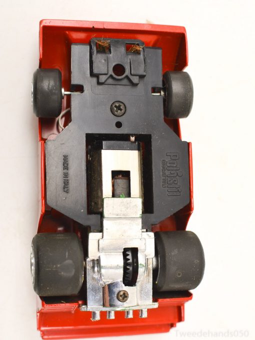 Detailed underside of a vintage red toy car showcasing its engineering and play features.