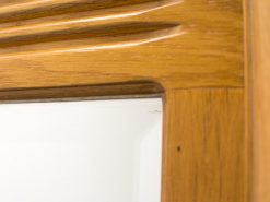 Elegant wooden mirror frame with intricate carvings and a warm, polished finish.