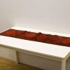 Handwoven Persian table runner with intricate diamond patterns in vibrant red hues.