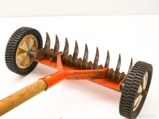 Vintage lawn mower with orange frame, sharp blades, and wooden handle for easy garden maintenance.