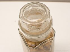 Vintage hexagonal glass jar filled with decorative wooden chips or stones.