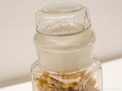 Vintage glass container with dried flowers and clear liquid for infusion or decoration.