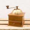 Vintage wooden coffee grinder with brass lid, perfect for traditional coffee lovers.