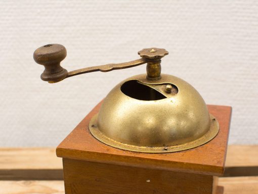 Elegant vintage brass coffee grinder with wooden handle, perfect for coffee enthusiasts.
