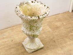 Antique white stone garden urn with floral motifs, perfect for rustic outdoor decor.