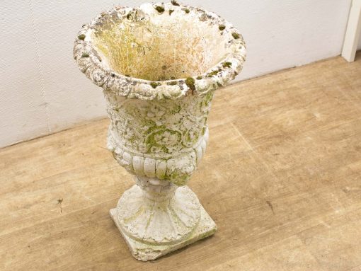 Antique white stone garden urn with floral motifs, perfect for rustic outdoor decor.