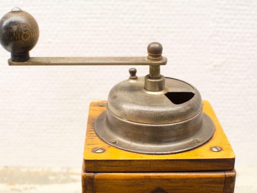 Vintage wooden coffee grinder with a metal grinding wheel and rustic charm for coffee enthusiasts.