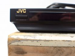Vintage JVC DVD player on weathered wood, blending nostalgia with modern design.