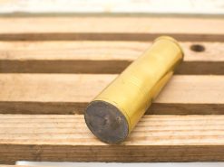 Vintage brass shotgun shell on rustic wooden table, showcasing craftsmanship and nostalgic appeal.