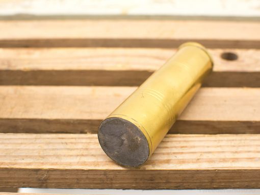 Vintage brass shotgun shell on rustic wooden table, showcasing craftsmanship and nostalgic appeal.