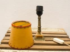 Charming vintage yellow lamp with ornate metallic base and red-stitched shade, perfect for cozy decor.
