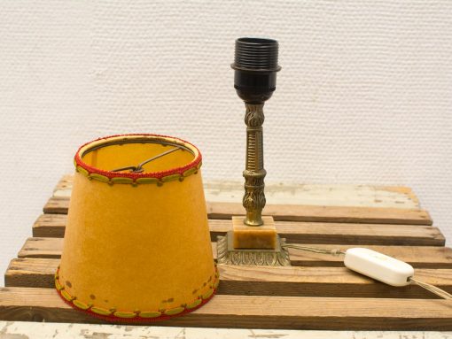 Charming vintage yellow lamp with ornate metallic base and red-stitched shade, perfect for cozy decor.