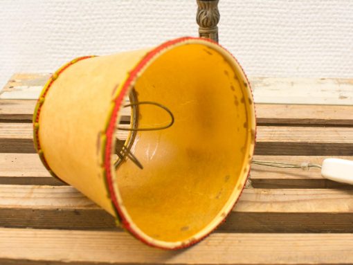 Vintage yellow lamp shade with red trim, perfect for DIY restoration and rustic decor.