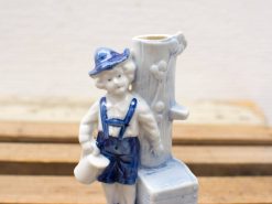 Charming porcelain figurine of a boy in traditional attire holding a whimsical pitcher.