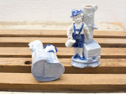 Charming blue and white ceramic boy figurine with vintage vase, evoking nostalgia and tradition.