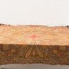 Elegant vintage paisley tablecloth with fringe in warm tones, perfect for any decor.