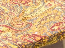 Vibrant paisley fabric in warm gold and deep red, perfect for elegant decor.