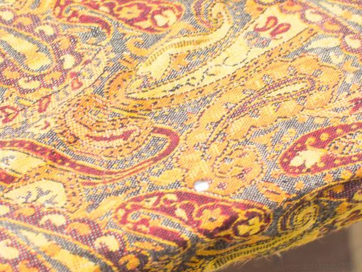 Vibrant paisley fabric in warm gold and deep red, perfect for elegant decor.