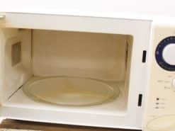 Compact white microwave featuring a transparent turntable and user-friendly controls for easy cooking.