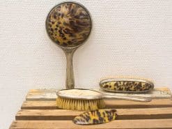 Elegant vintage grooming set with tortoiseshell design, including a mirror, brush, and comb.