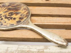 Vintage tortoiseshell hand mirror with elegant design, perfect for decor and beauty routines.
