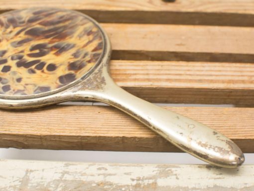 Vintage tortoiseshell hand mirror with elegant design, perfect for decor and beauty routines.