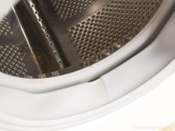 Stainless steel washing machine drum interior showing signs of use and maintenance needs.