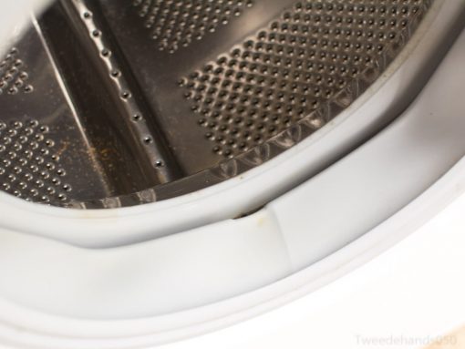 Stainless steel washing machine drum interior showing signs of use and maintenance needs.