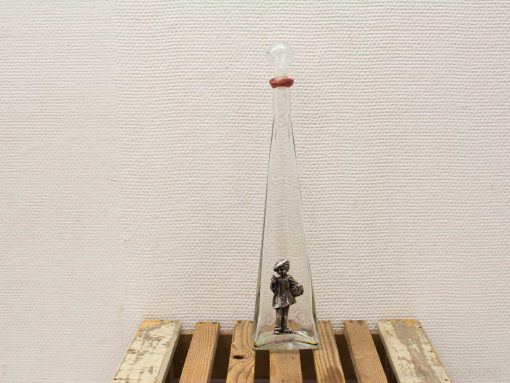 Elegant vintage glass decanter with playful child figure inside, perfect for decor and nostalgia.