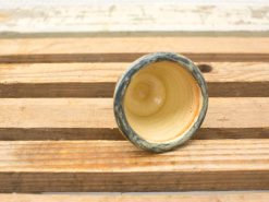 Handmade ceramic cup with earthy green-blue exterior and creamy interior, perfect for daily use.