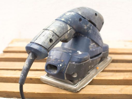 Ergonomic handheld electric sander for woodworking and DIY projects, showing signs of frequent use.