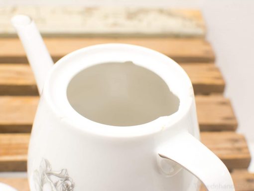 Vintage porcelain teapot with a charming chip, perfect for classic tea service.