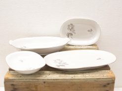 Vintage ceramic dish collection featuring elegant rose designs on a rustic wooden surface.
