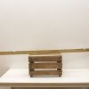 Rustic wooden crate with beam atop a minimalist white table, showcasing simple, functional design.