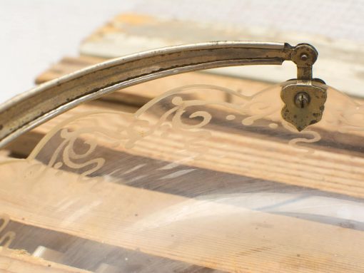 Elegant etched glass dome with vintage handle, set against a warm wooden backdrop.