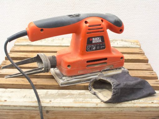 Black & Decker sander on rustic wood, featuring ergonomic grip and dust bag for clean sanding.