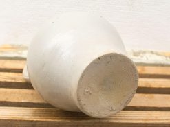 Elegant hand-crafted ceramic pot with matte finish on rustic wooden slats.