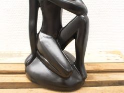Elegant black sculpture of a kneeling man, embodying contemplation and refined artistic expression.