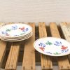 Colorful hand-painted ceramic plates stacked on a rustic wooden surface for charming decor.