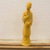 Intricately carved yellow wooden statue, showcasing cultural craftsmanship and serene elegance.