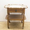 Elegant vintage wooden side table with floral inlay, drawer, and turned legs on wheels.