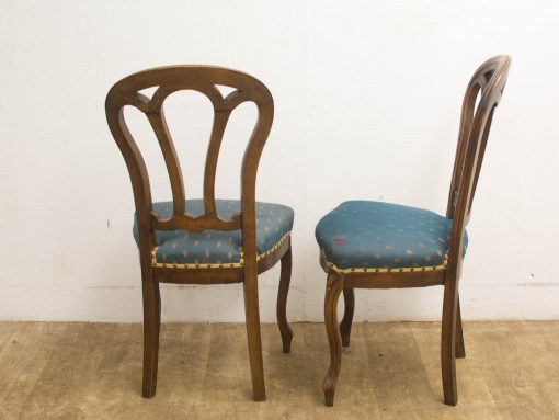 Elegant vintage wooden chairs with luxurious blue and gold upholstery, perfect for nostalgic interiors.