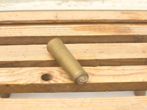 Vintage brass cylinder on rustic wood, showcasing elegant design and charming wear. Perfect decor piece.