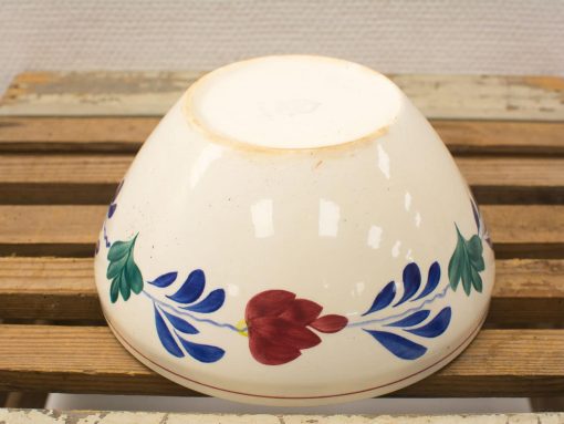 Vintage floral ceramic bowl on rustic wood, showcasing artisanal craftsmanship and history.