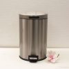 Sleek stainless steel trash can with foot pedal, lid, and flower accent for modern decor.