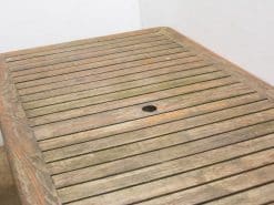 Rustic wooden outdoor table with umbrella hole, perfect for gardens and patios.