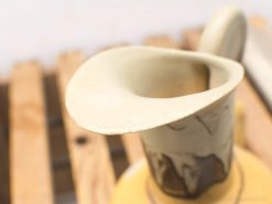 Rustic ceramic pitcher with elegant spout, showcasing earthy tones and artisanal craftsmanship.