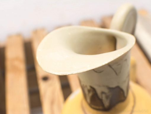Rustic ceramic pitcher with elegant spout, showcasing earthy tones and artisanal craftsmanship.